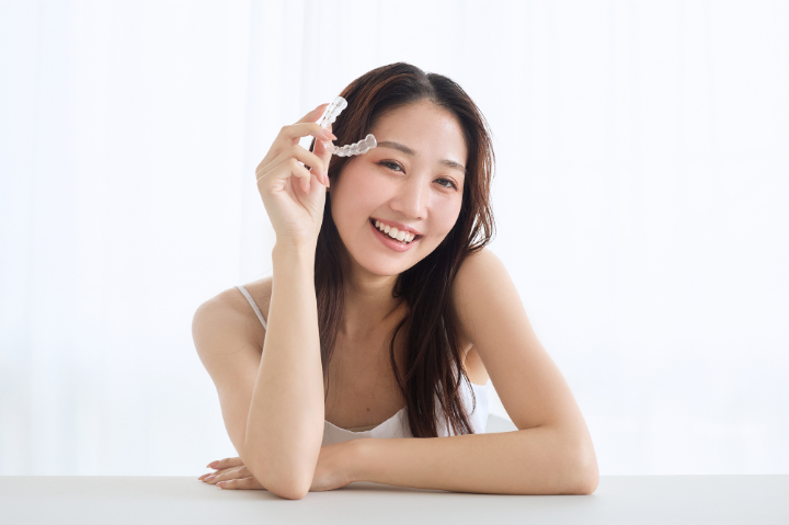 マウスピースを手にして笑顔を見せる女性