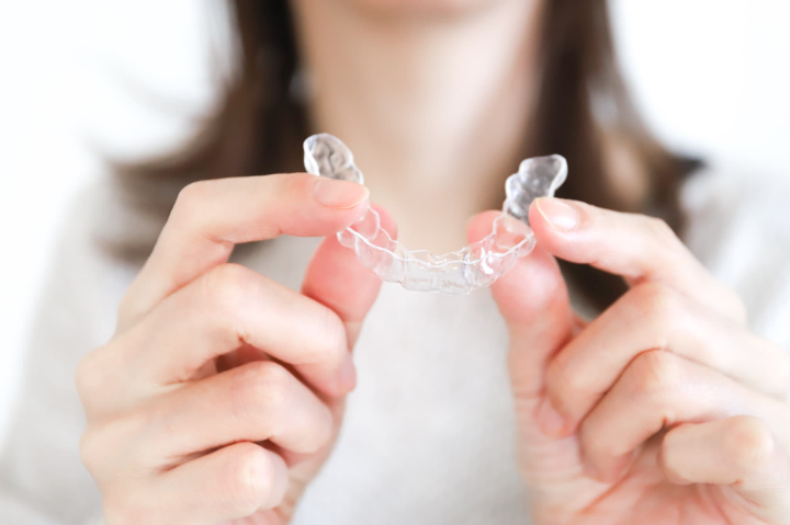 リテーナーを両手で持つ女性の手元