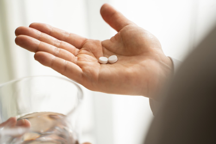 コップを片手に鎮痛剤を乗せた手のひら