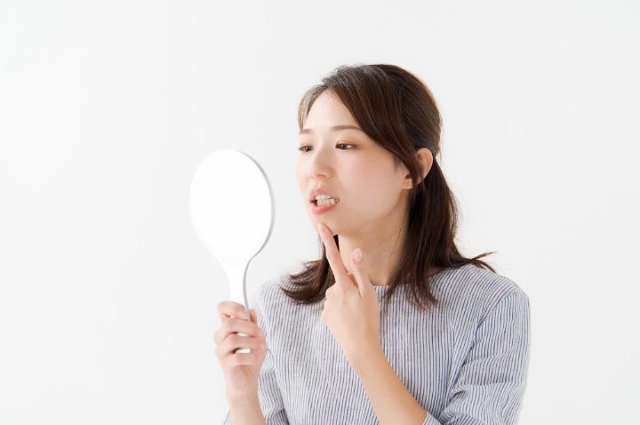 矯正後の後戻りが気になり鏡を見る女性