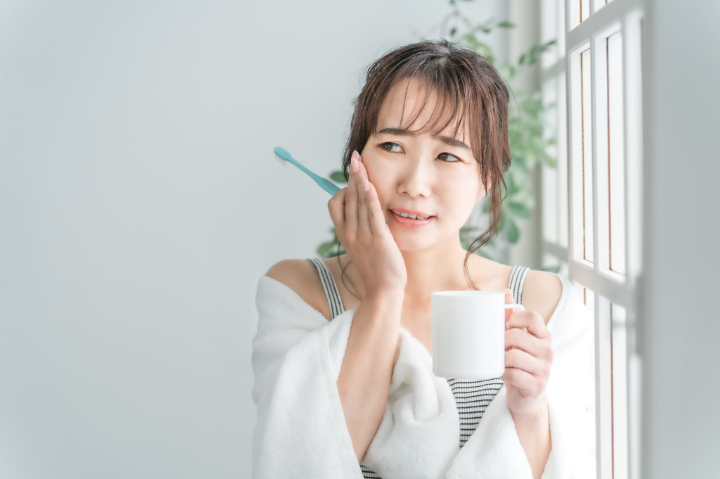 虫歯ができて歯みがきをすると痛む女性