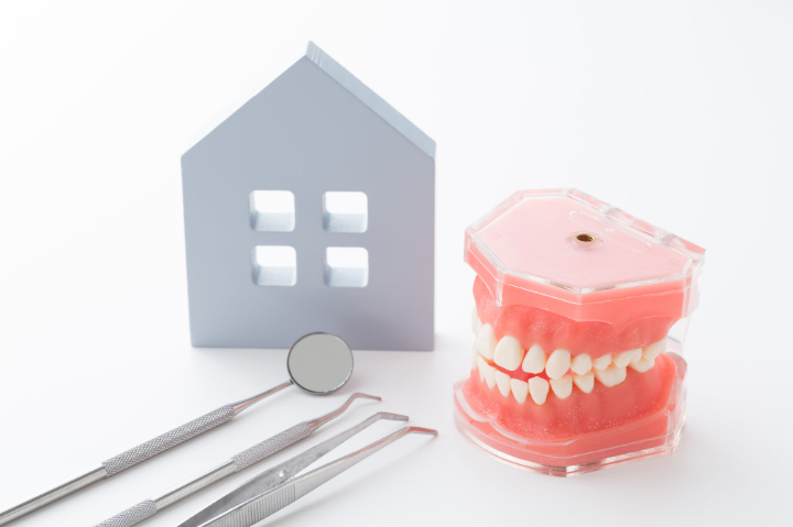 訪問歯科での治療を示す家と歯の模型に歯科医療器具