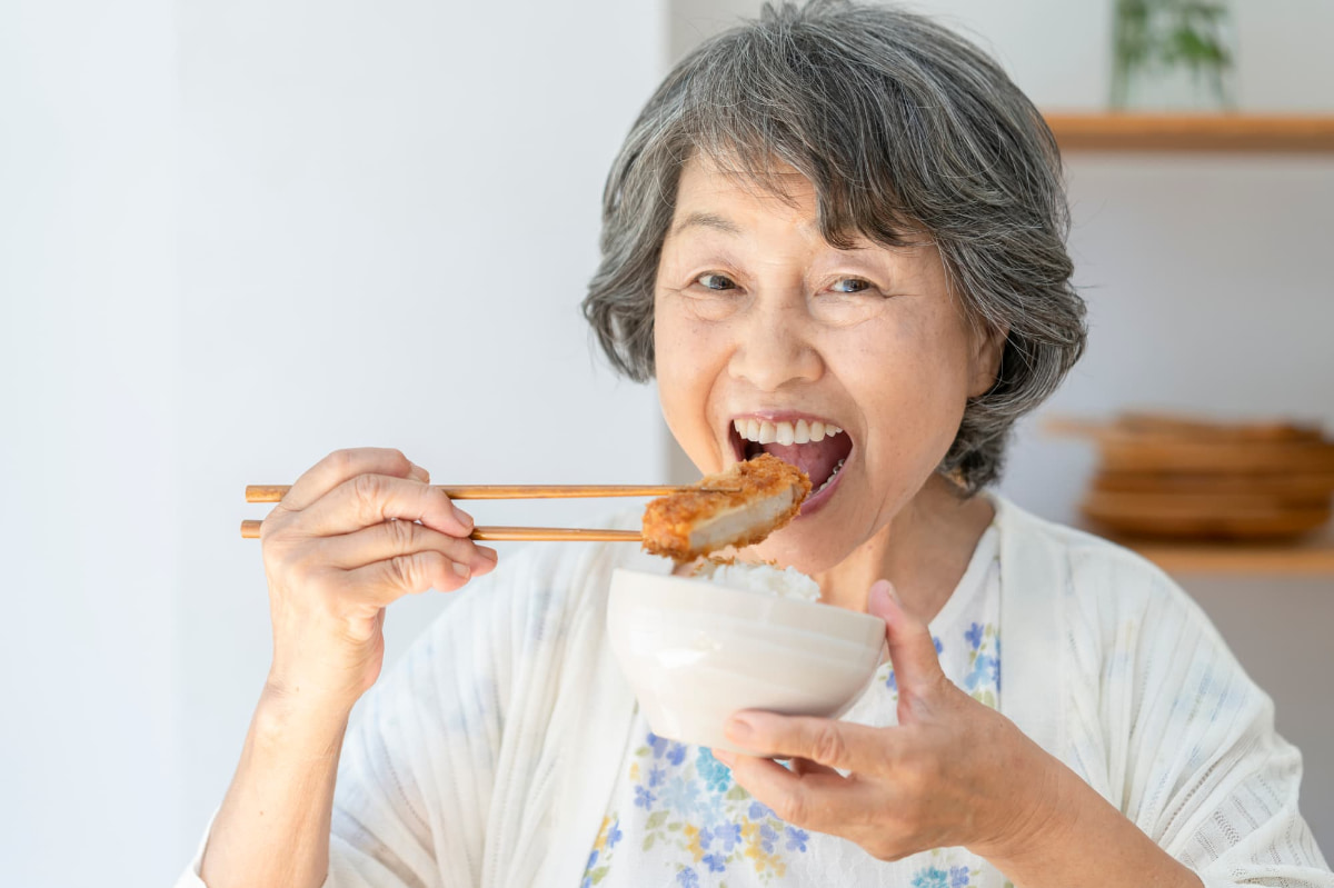 奥歯でしっかりと噛んで食事をするシニア女性